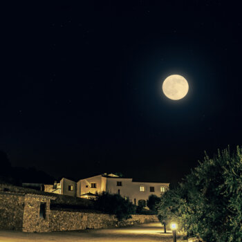 Exterior of Masia Cabellut vineyard estate with surrounding valley in a full moon.